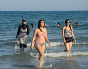 ブルキニやビキニ姿の女性が一緒に海水浴を楽しんでいる海＝2016年8月、チュニジア・ビゼルト【ＡＦＰ時事】
